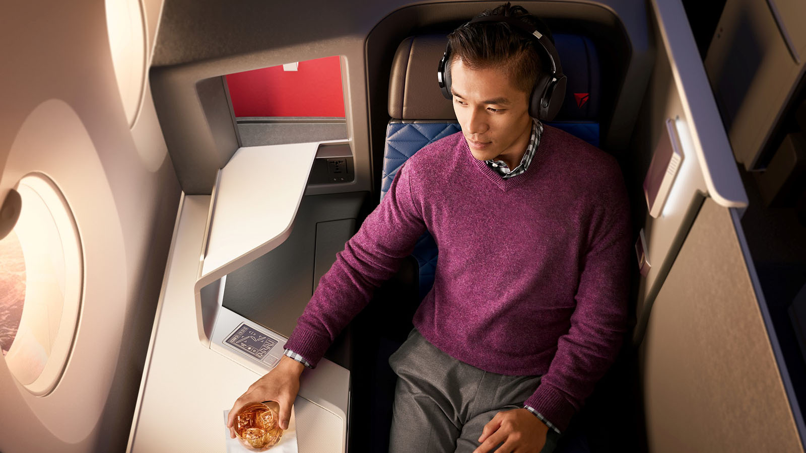 Passenger sits in Delta One, relaxing with a drink