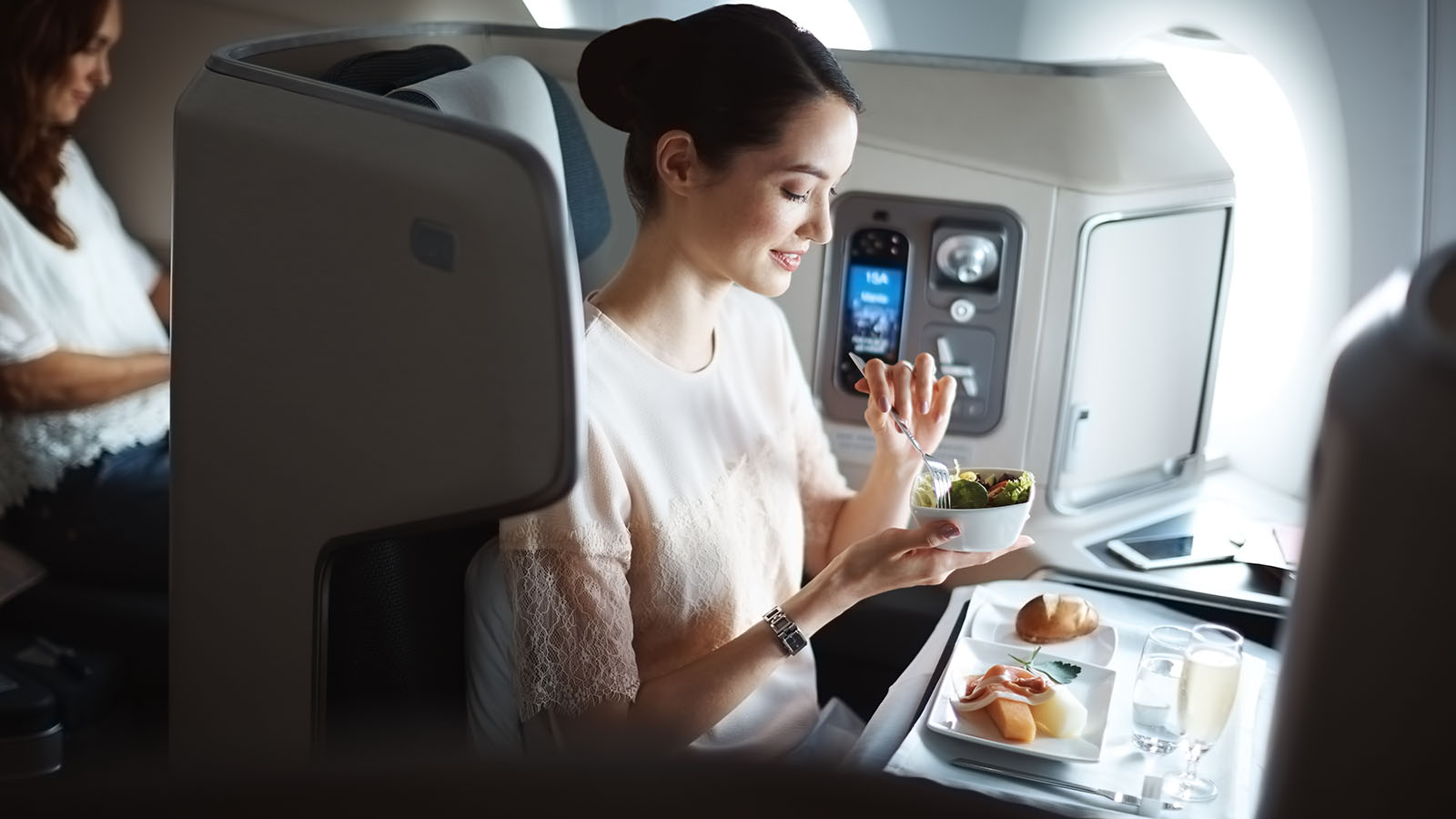 Passenger eating a meal in Cathay Pacific Business Class - bookable if you buy Cathay miles.