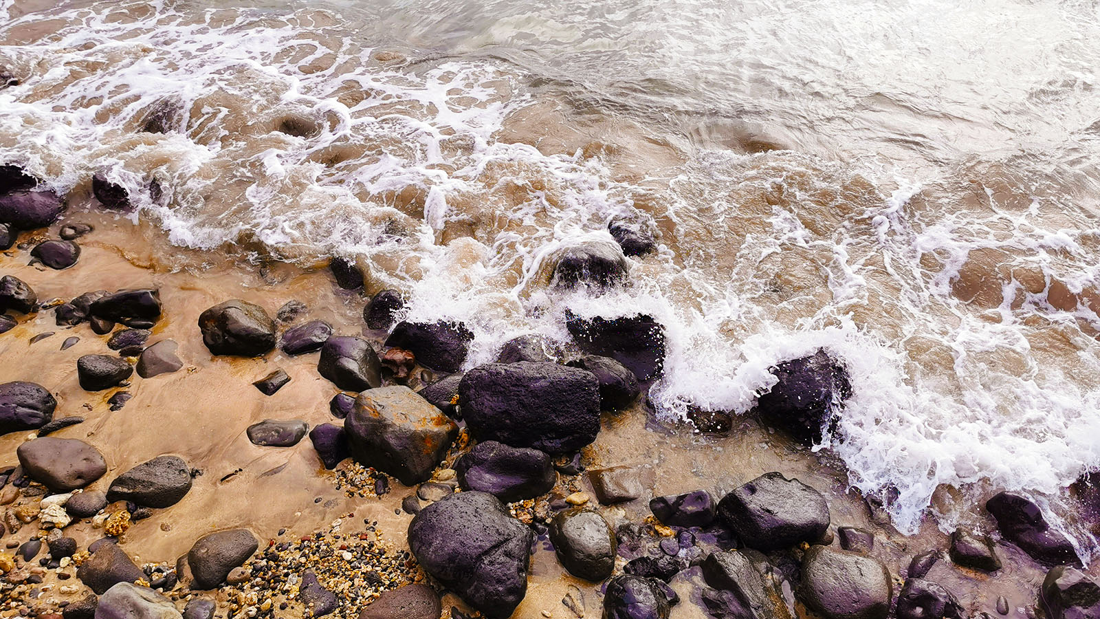 Water rolling over sand and rocks in Maui, Hawaii