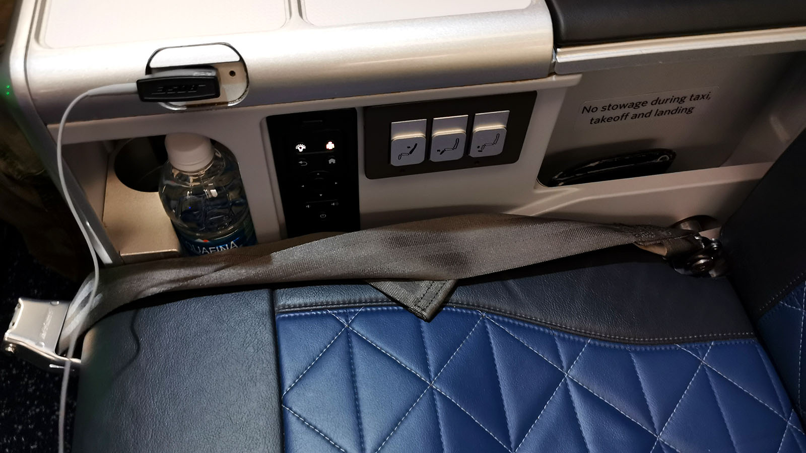 Seat controls and water bottle in Delta A330-900neo Comfort+