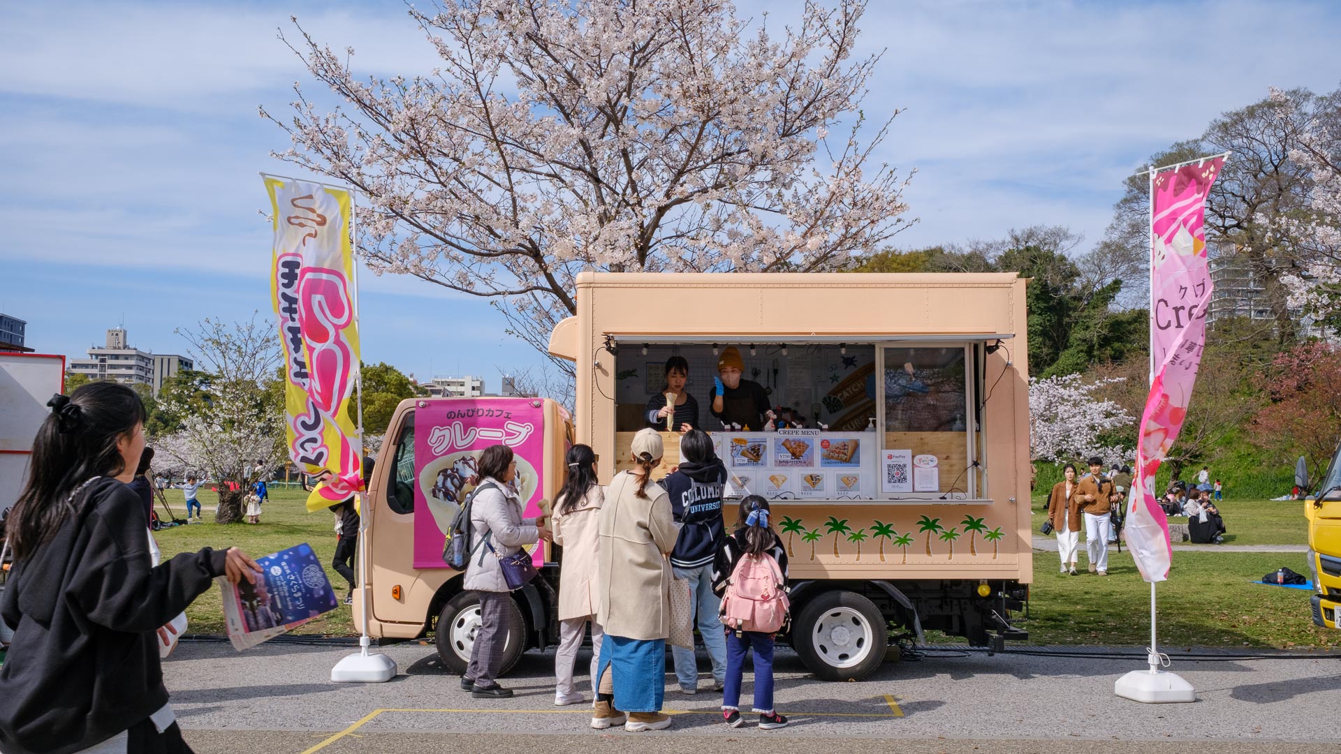 Visitors lining up at a food truck under cherry blossoms at Maizuru Park in Fukuoka